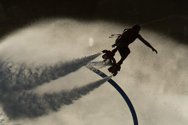 Man hovering with a water-propelled board attached to a jet ski