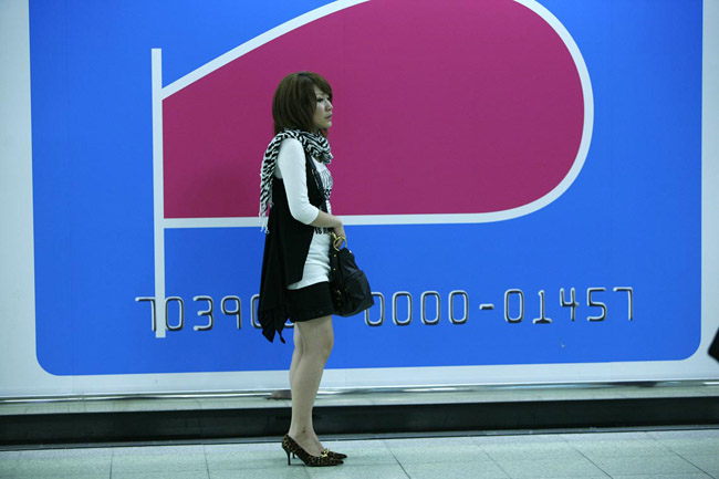 Woman waiting in front of a bill board at Shinjuku station